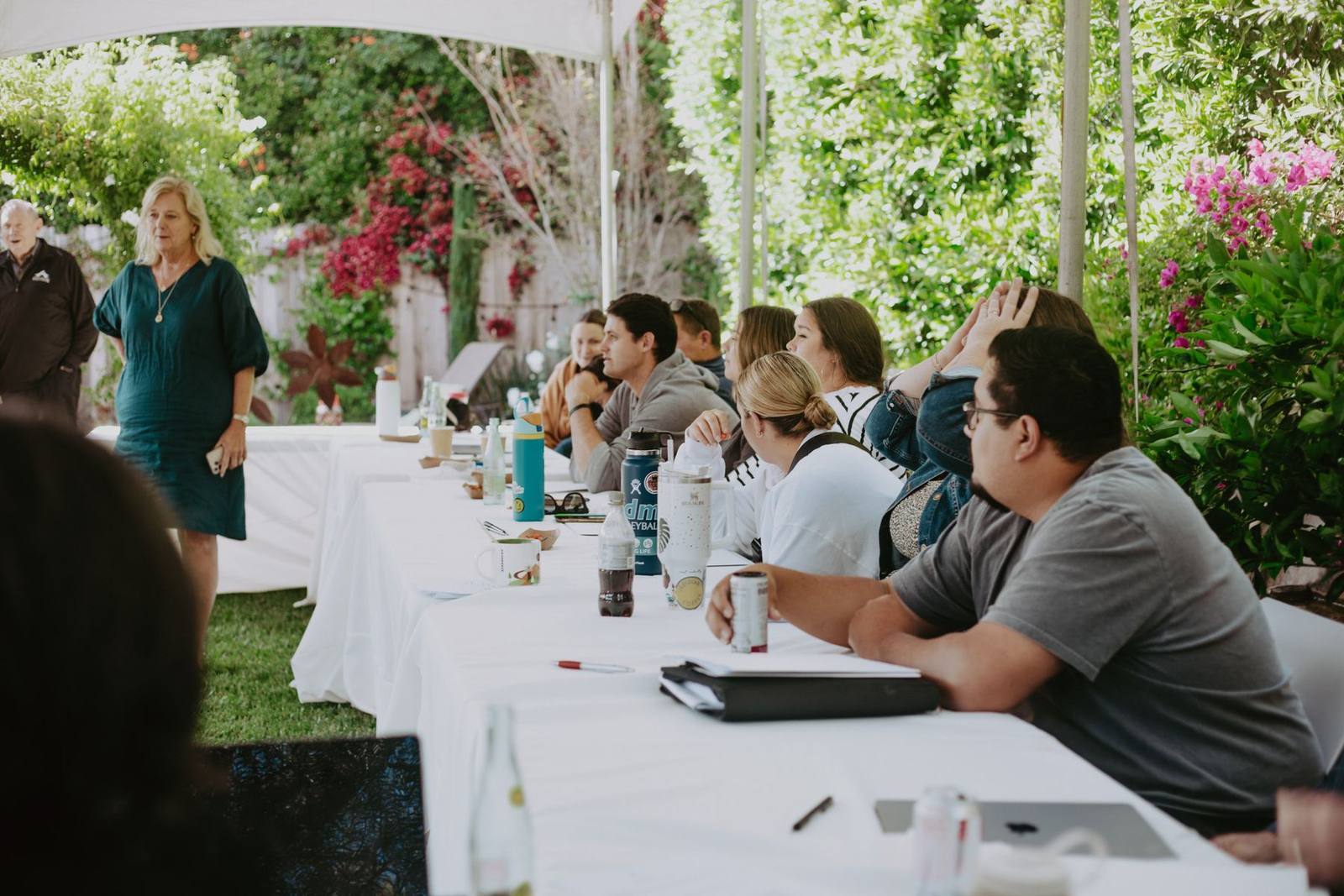 Dr. Bergstrom teaching a group seated at long tables in a garden